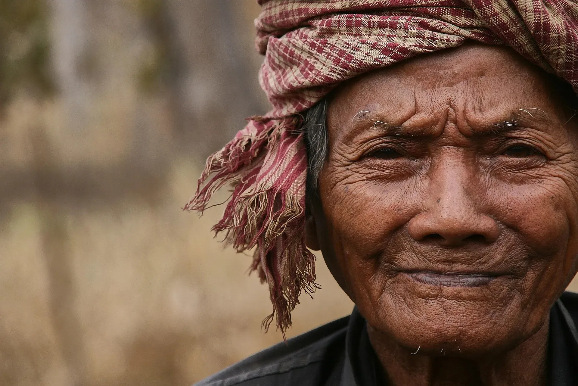 An elderly man in a checked krama
