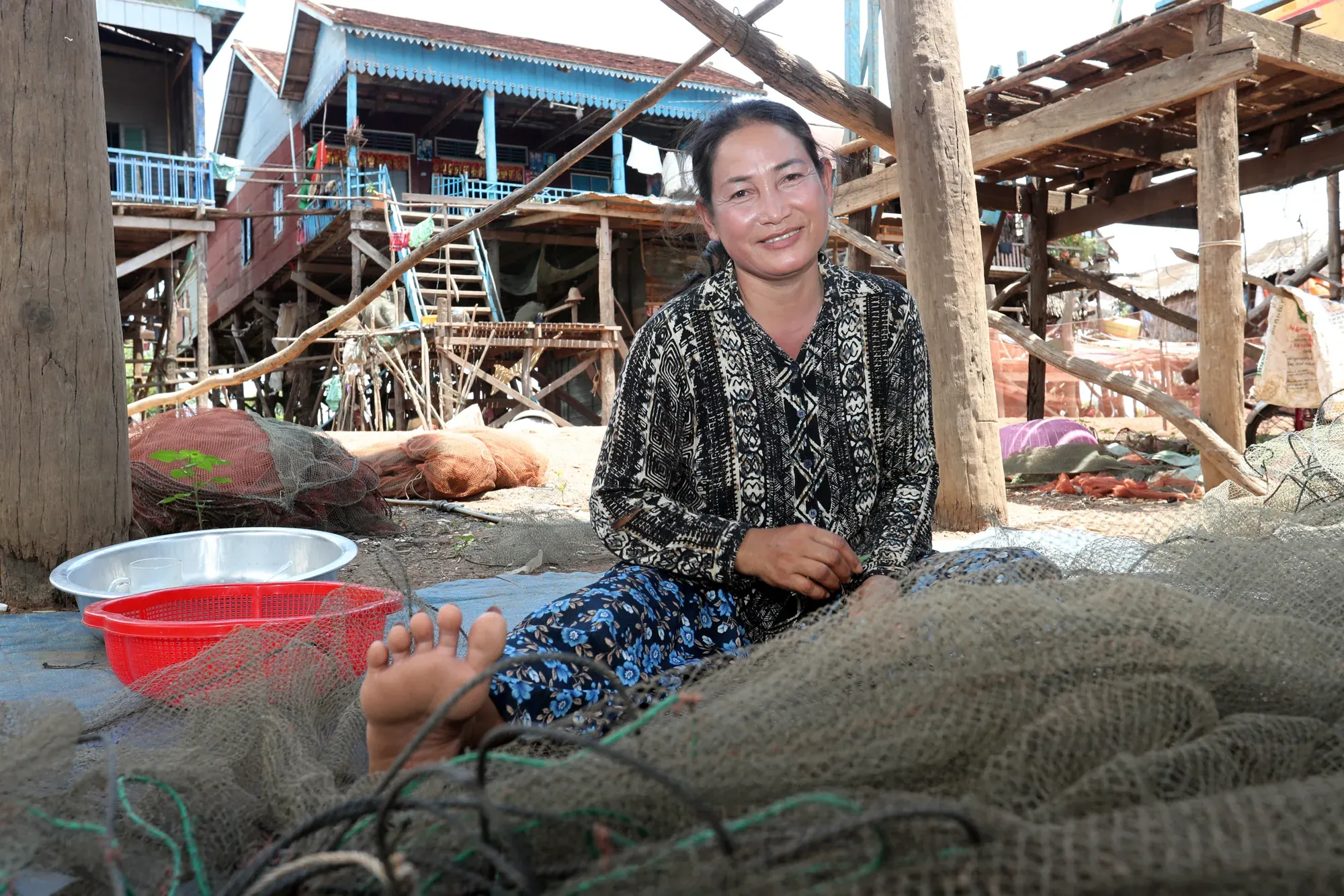 A woman mending fishing nets at home in Kompong Khleang
