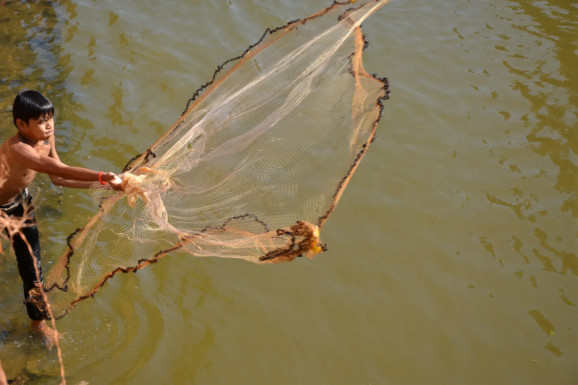 A boy casts a fishing net at Kompong Phluk