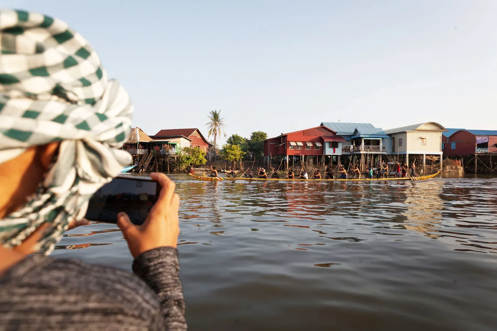 A guest photographs the stilt houses from the boat